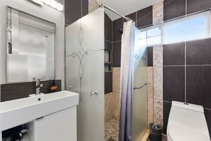 A modern bathroom with a white sink, a glass shower enclosure, and a toilet. - Cool Vibes SoCo Townhome! (Austin)