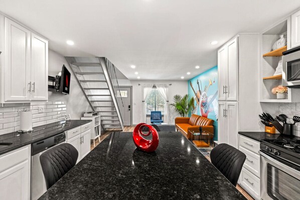 A modern kitchen with a black granite countertop, white cabinets, and a red decorative bowl.