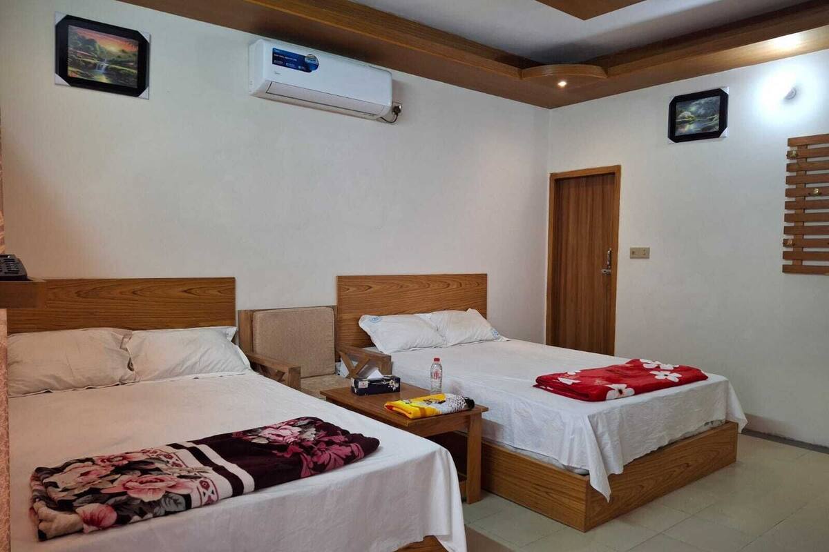 A room with two wooden beds, a wooden ceiling, an air conditioning unit, and a door.