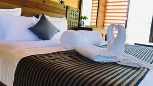 A neatly made bed with a striped bedspread and a headboard with a circular pattern. - Ella Crest by Aloft (Ella)