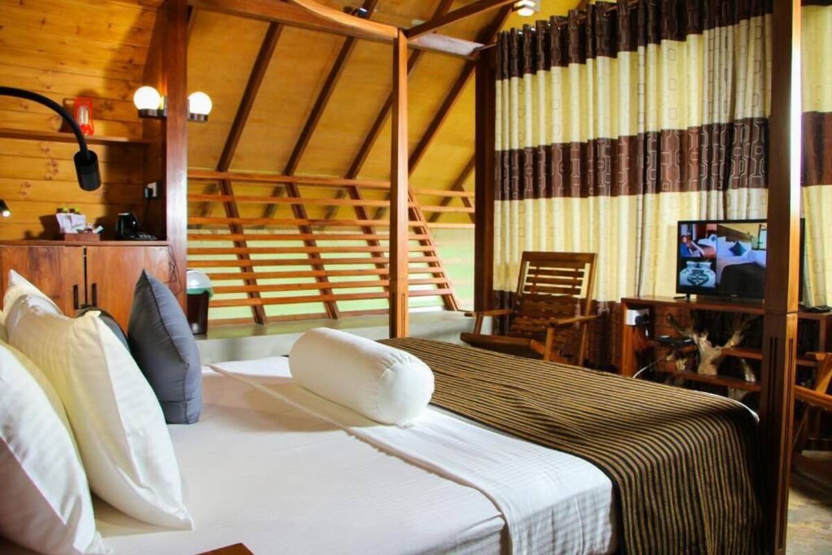Een gezellige kamer met een bed, een houten hoofdbord, een televisie en een bureau met een stoel.