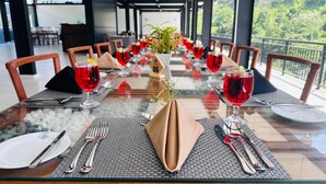 A dining table set for a meal with red drinks, white plates, and silverware. - Ella Crest by Aloft (Ella)