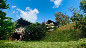 A house with a sloped roof and a balcony, surrounded by lush greenery and a clear blue sky. - Ella Crest by Aloft (Ella)