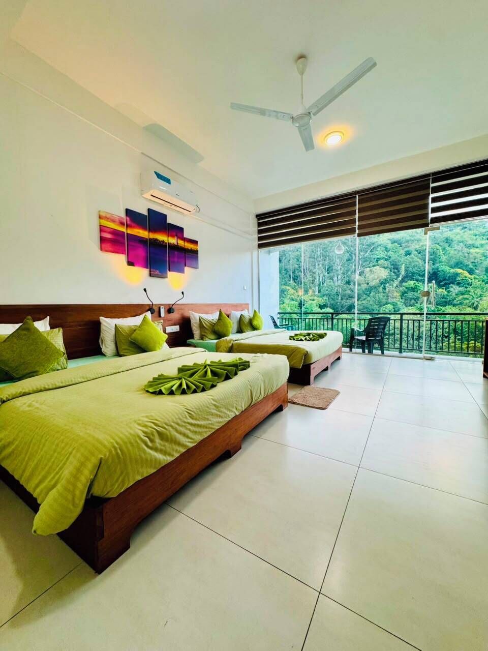 A hotel room with two beds, a ceiling fan, an air conditioning unit, and a balcony with a view of the forest.