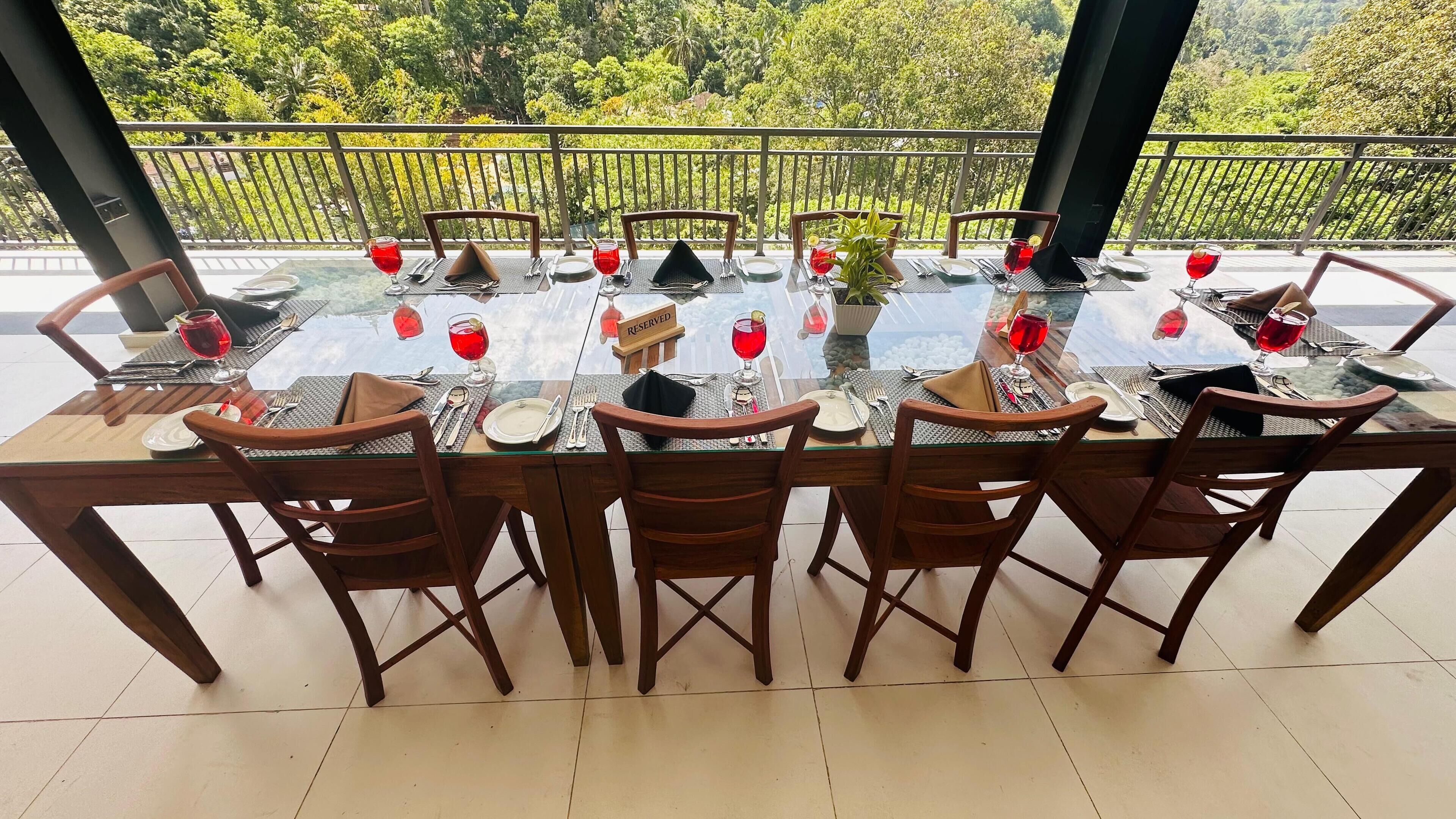 A dining area with a glass table set for six, surrounded by wooden chairs.