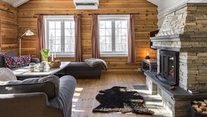 A cozy log cabin interior with a fireplace, wooden walls, and a sofa by the windows. - Fjälldrömmen by Interhome (Storlien)