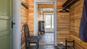 A log cabin interior with a stone floor, a fireplace, a chair, and a coat rack. - Fjälldrömmen by Interhome (Storlien)