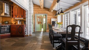 A modern kitchen with wooden cabinets, a stone floor, and a dining area with a table set for six. - Fjälldrömmen by Interhome (Storlien)