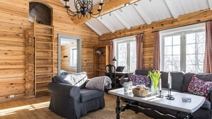A cozy log cabin interior with a sofa, a table, and a bookshelf. - Fjälldrömmen by Interhome (Storlien)