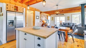 A modern kitchen with wooden beams, a stainless steel refrigerator, and a wooden island with a bowl. - Paddle, Swim & Hike: Family Lake House in Vermont (Tinmouth)