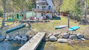 A two-story house with a balcony, a dock, and a small boat. - Paddle, Swim & Hike: Family Lake House in Vermont (Tinmouth)