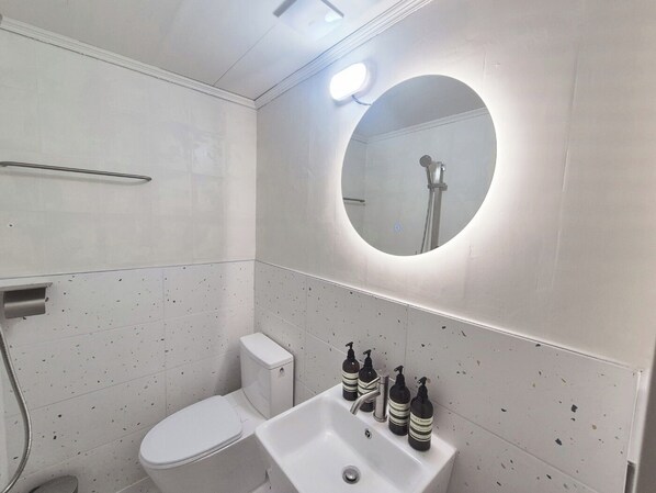 Uma casa de banho moderna com sanita, lavatório e chuveiro.