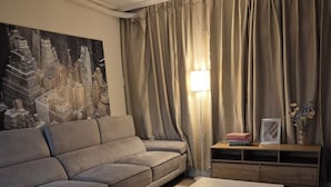 Un salon avec un canapé, une table basse, une lampe et un cadre photo posé sur une console.