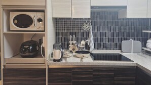 Une cuisine compacte équipée d’un four à micro-ondes, d’une bouilloire, d’un grille-pain et d’un petit évier.