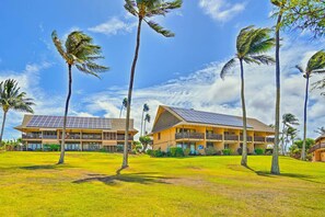 Un hôtel composé d’un bâtiment à deux étages, doté de panneaux solaires sur le toit et d’une pelouse verdoyante agrémentée de palmiers.