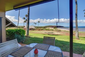 Une terrasse avec une table et des chaises, donnant sur une plage et des palmiers.
