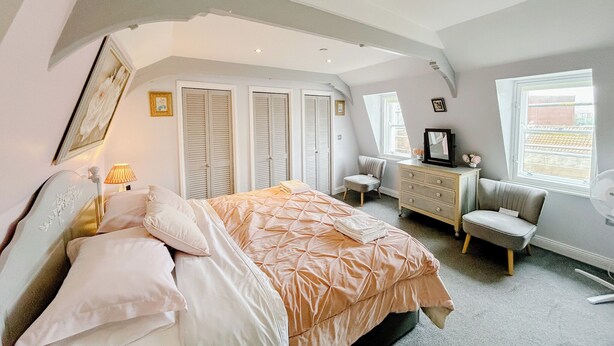 A bedroom with a bed, dresser, chair, and a window.