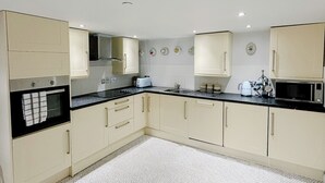 A modern kitchen with white cabinets, black countertops, and patterned floor tiles.