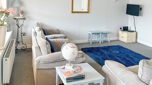 A living room with a sofa, coffee table, and a blue rug.