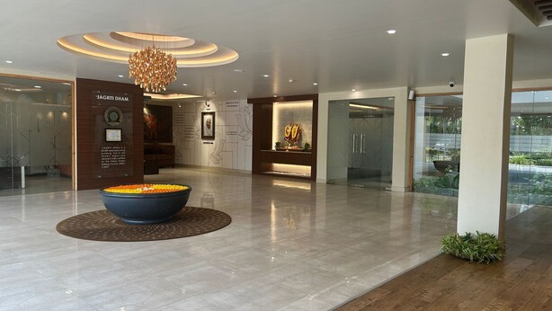 A modern lobby with a large decorative bowl, a chandelier, and a reception desk. - Jagriti Dham (Alipur)