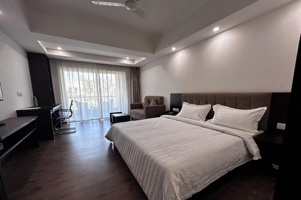 Ein modernes Hotelzimmer mit einem großen Bett, einem Schreibtisch und einem Sessel.
