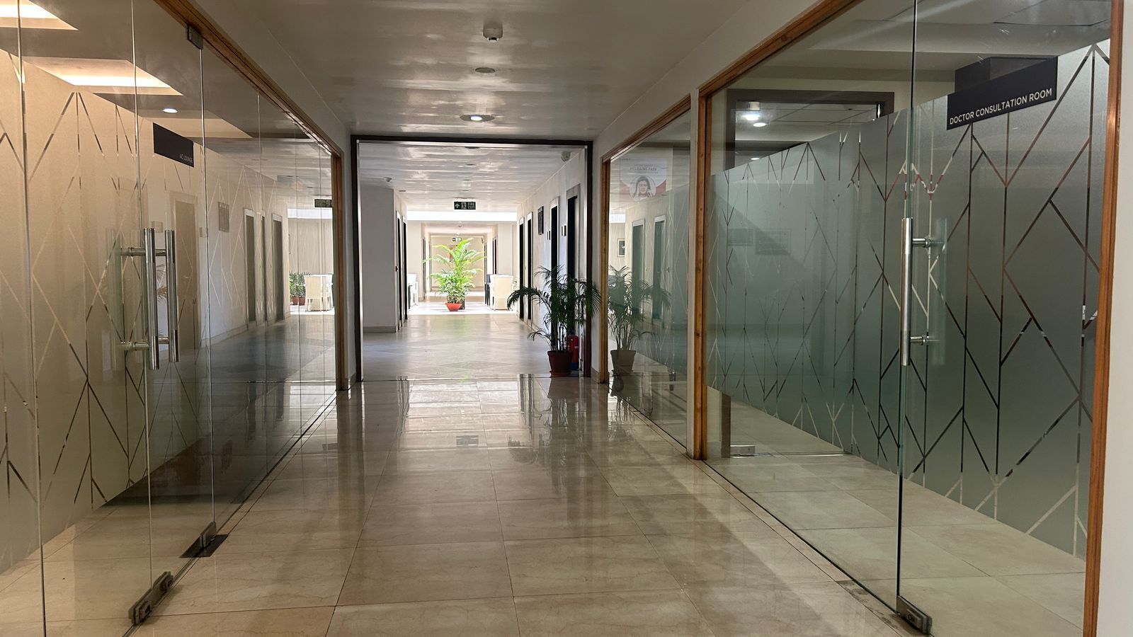 Un pasillo con paredes de vidrio, suelo de baldosas y un letrero para consulta médica.