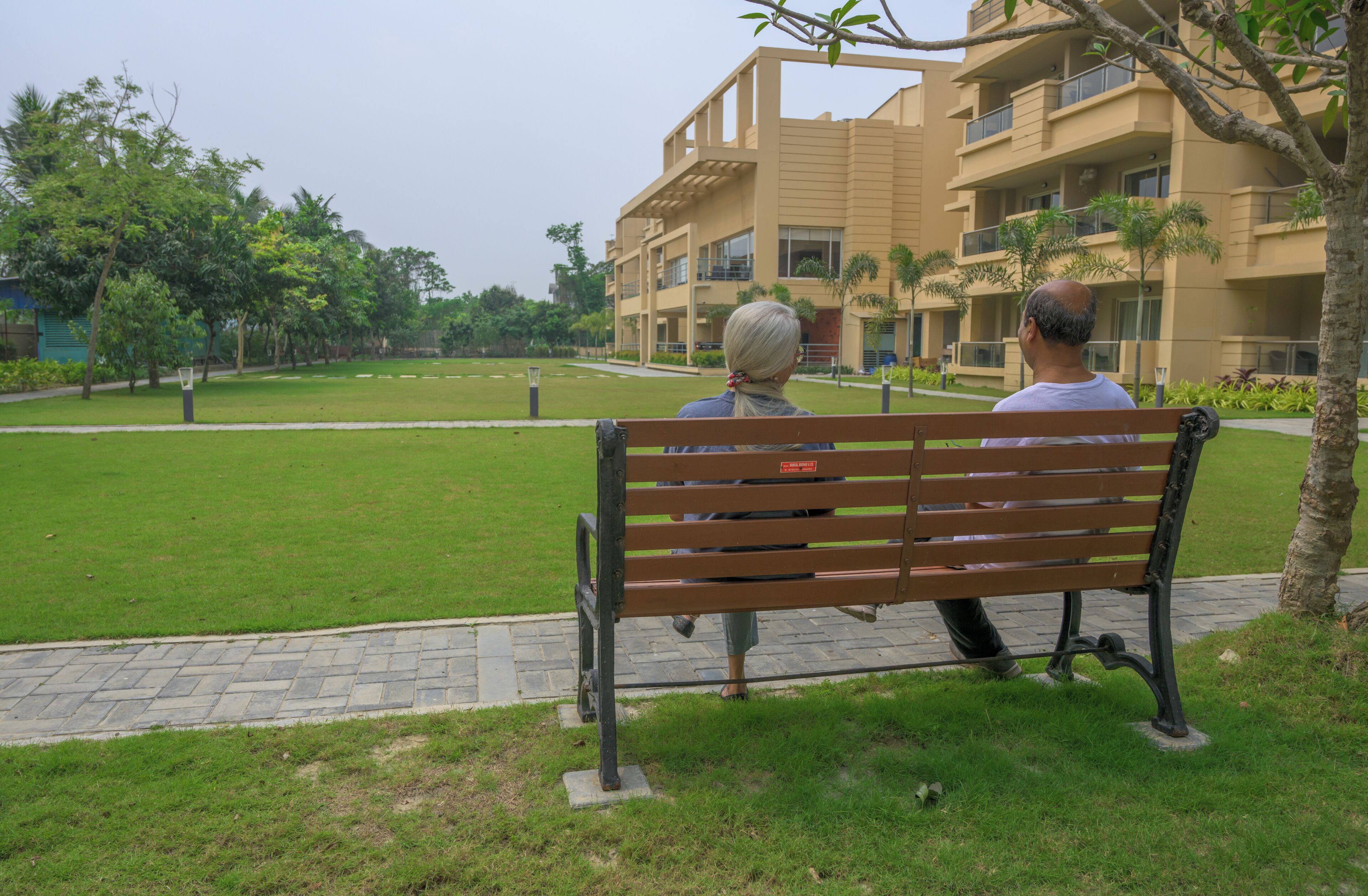 A bench in a park with a building in the background.