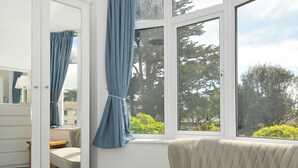 A bedroom with a large window, a sofa, a wardrobe, and a mirror. - Falmouth Bay 1 (Falmouth)