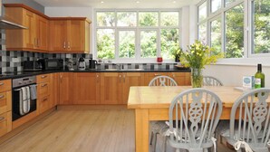 A modern kitchen with wooden cabinets, a black countertop, and a dining area with a wooden table and chairs. - Falmouth Bay 1 (Falmouth)