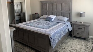 A bedroom with a large bed, a nightstand, a lamp, and a wardrobe. - Charming 2-bedroom condo in delightful Chelsea with WiFi, AC (Chelsea)