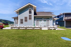 A two-story house with a garage, a covered patio, and a well-maintained lawn. - Charming waterfront home in Greenbank with direct beach access (Greenbank)