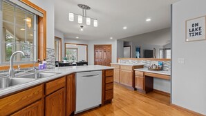 A modern kitchen with wooden cabinets, a stainless steel sink, and a built-in dishwasher. - Oak Haven Retreat, Oak Haven Retreat  - Charming Green Lake Property (Princeton)