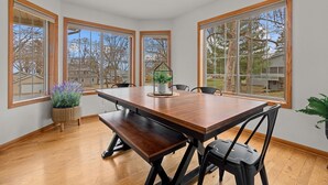 A dining room with a wooden table and chairs, large windows, and a view of the neighborhood. - Oak Haven Retreat, Oak Haven Retreat  - Charming Green Lake Property (Princeton)