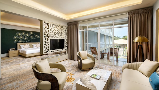 A modern hotel room with a bed, seating area, TV, and a balcony with a view. - Avenra Garden (Negombo)