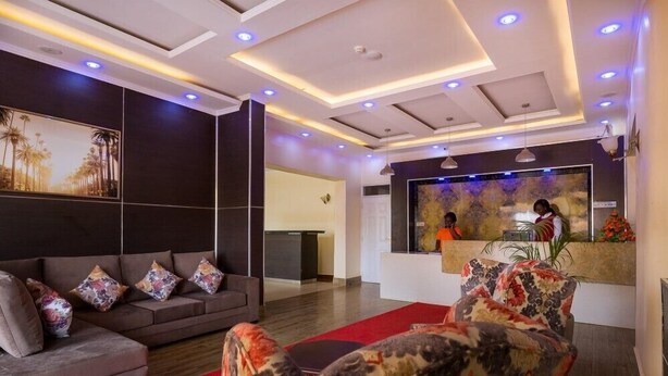 A modern hotel lobby with a reception desk, a sofa, and a patterned armchair. - The Junction Hotel & Suites (Kisii)