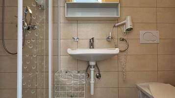 A modern bathroom with a glass shower enclosure, a white sink with a mirror above it, and a toilet.