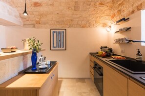 Eine Küche mit Steinwand, Holzschränken, einer schwarzen Arbeitsplatte und einer Hängeleuchte.