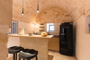 A kitchen with a stone ceiling, a black refrigerator, and a wooden countertop. - Casale Palazzina Tommaso con Piscina (Fasano)