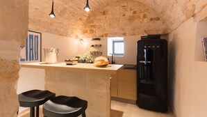 A kitchen with a stone ceiling, a black refrigerator, and a wooden countertop. - Casale Palazzina Tommaso con Piscina (Fasano)