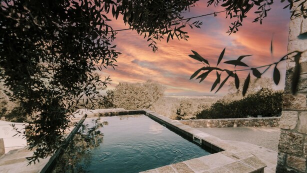 A rectangular stone pool with a stone border, surrounded by stone walls and vegetation. - Casale Palazzina Tommaso con Piscina (Fasano)