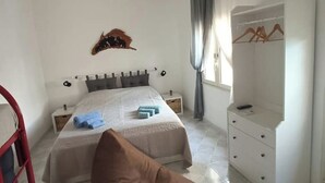 Una camera da letto con un letto, comodini, un armadio e una lampada a sospensione.