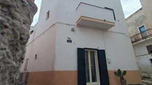 A modern building with a flat roof, a small balcony, and a door with shutters. - Nardò historical center (Nardò)