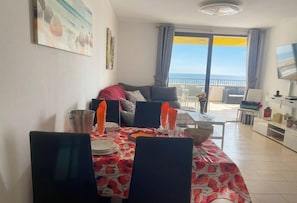 Een eetgedeelte met een tafel voor vier personen, een bank en een balkon met uitzicht.