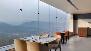 Comedor con mesa dispuesta para cuatro, ventanas amplias que ofrecen vistas a la montaña y un diseño interior moderno.