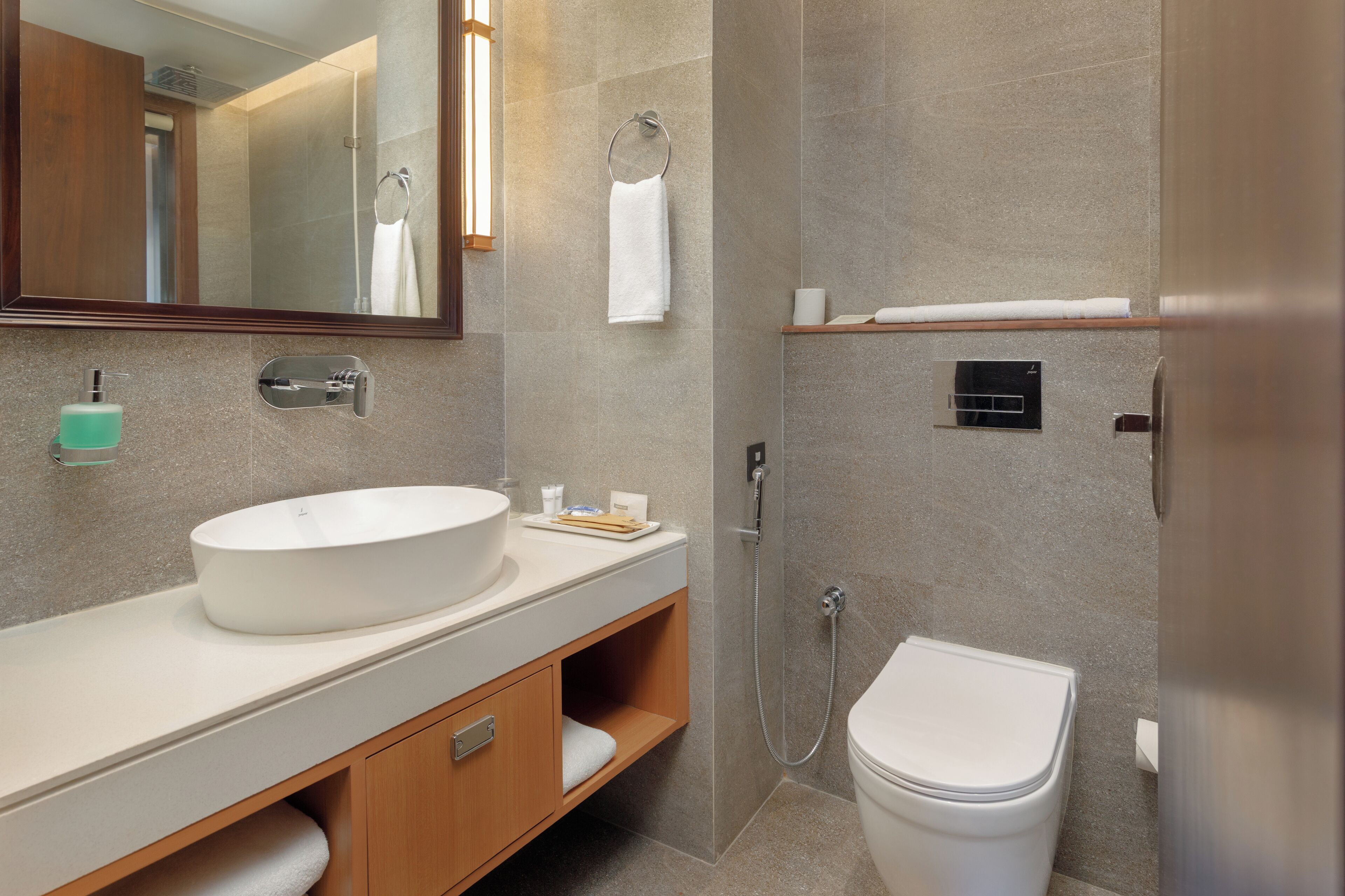 Un baño moderno con un lavamanos grande, espejo y retrete.