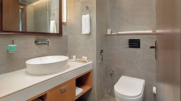 Un baño moderno con un lavamanos grande, espejo y retrete.