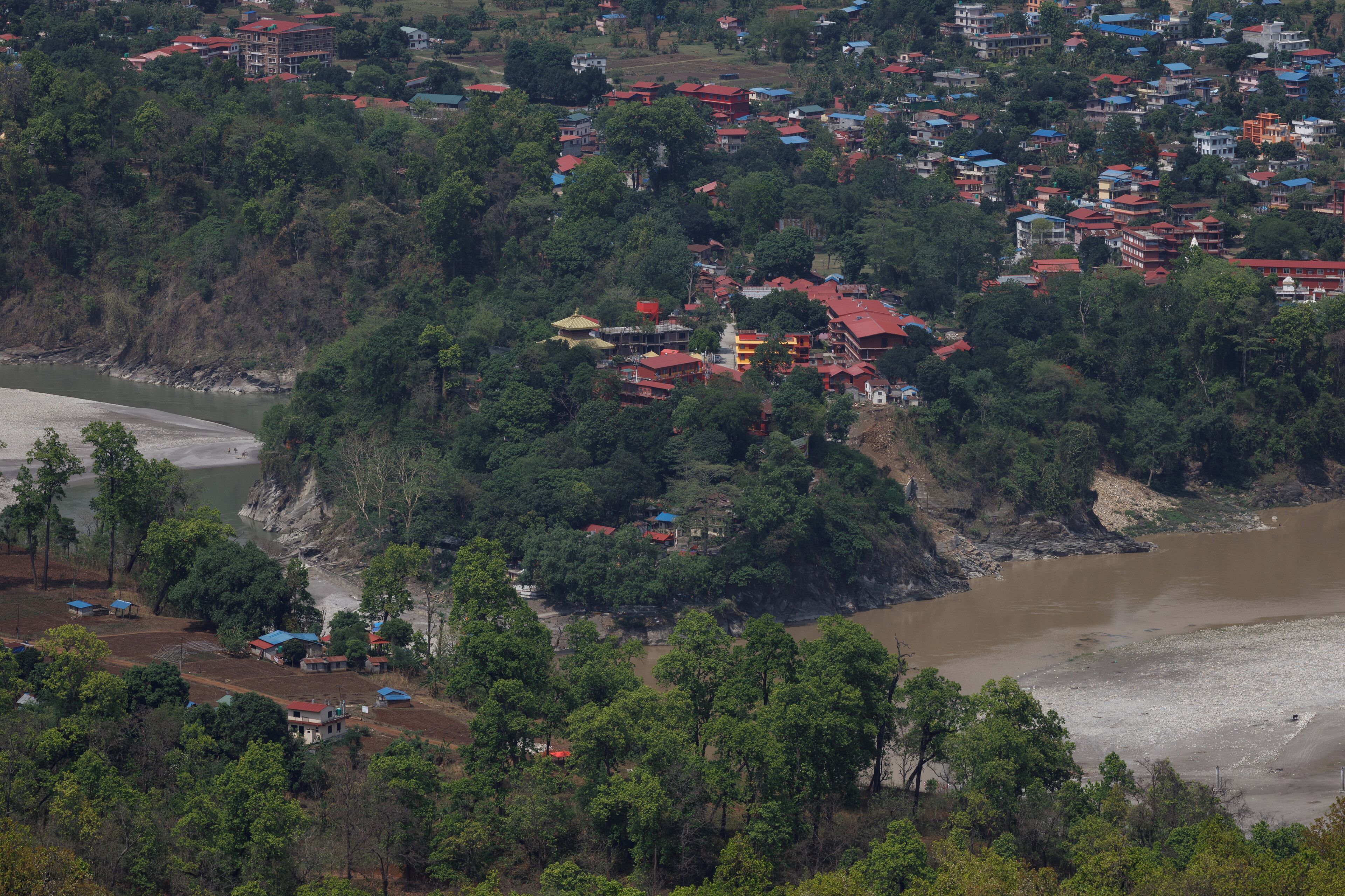 A coastal town with buildings on a hillside overlooking a river.