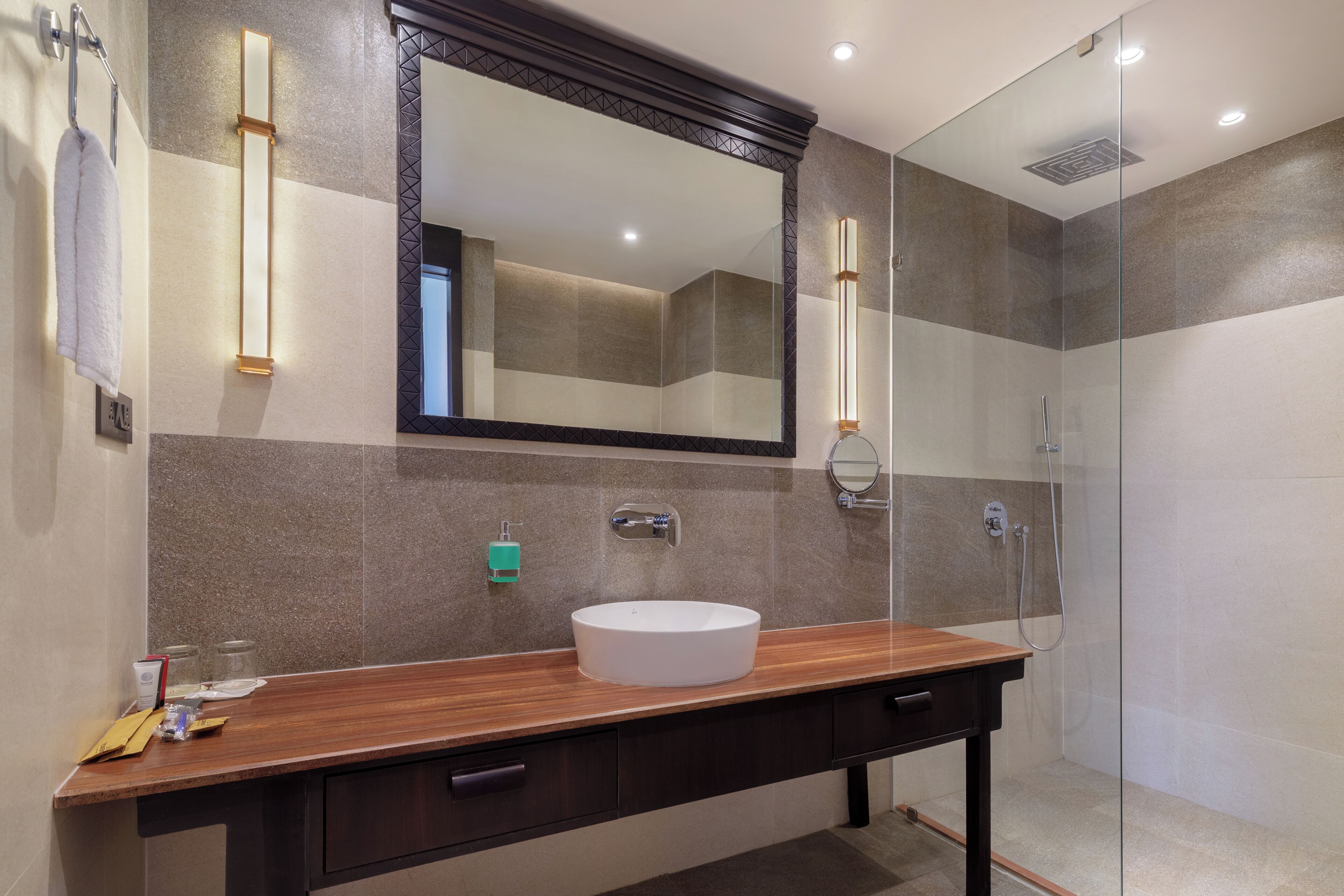 A modern bathroom with a wooden vanity, a large mirror, a round sink, and a glass shower enclosure.