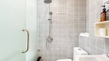 Uma casa de banho moderna com chuveiro, sanita e lavatório.