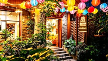 A brightly lit entrance with colorful paper lanterns, a stone wall, and a wooden gate.